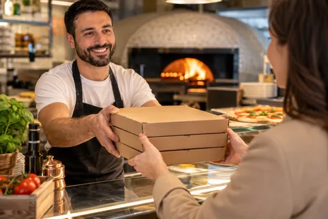 Übergabe von Pizzakartons an der Theke